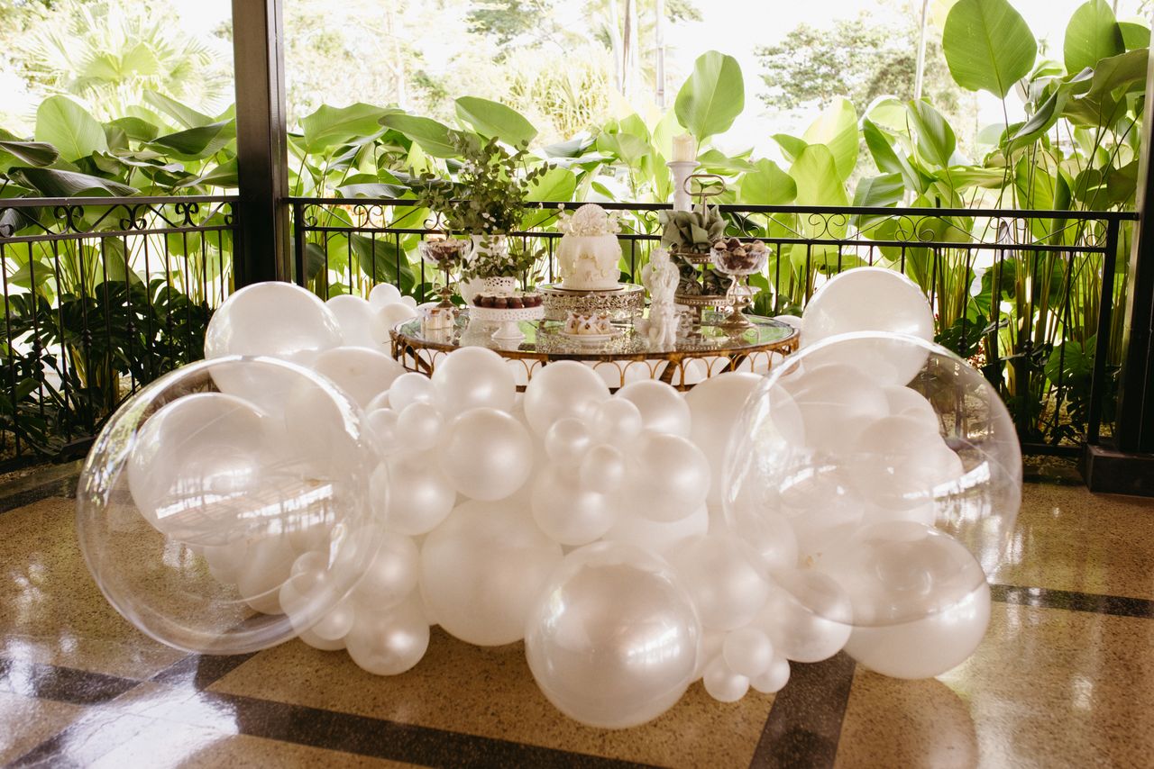 Charming outdoor event setup featuring white balloons and elegant decor against lush greenery.